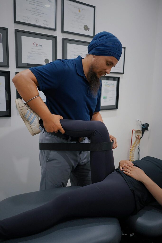 Male physiotherapist with turban helping female patient with leg rehabilitation exercise in a modern clinic setting.