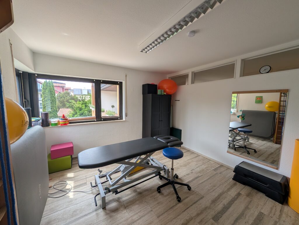 Behandlungsraum mit Therapieliege und Fensterfront