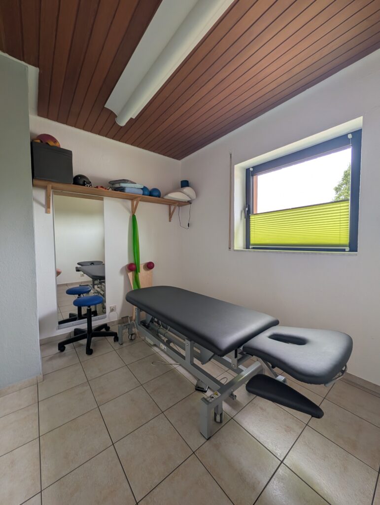 Behandlungsraum mit Therapieliege und Holzdecke