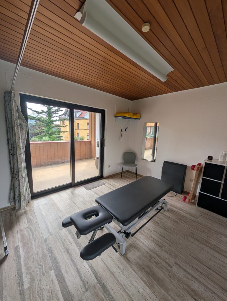 Behandlungsraum mit Therapieliege und Zugang zur Terrasse